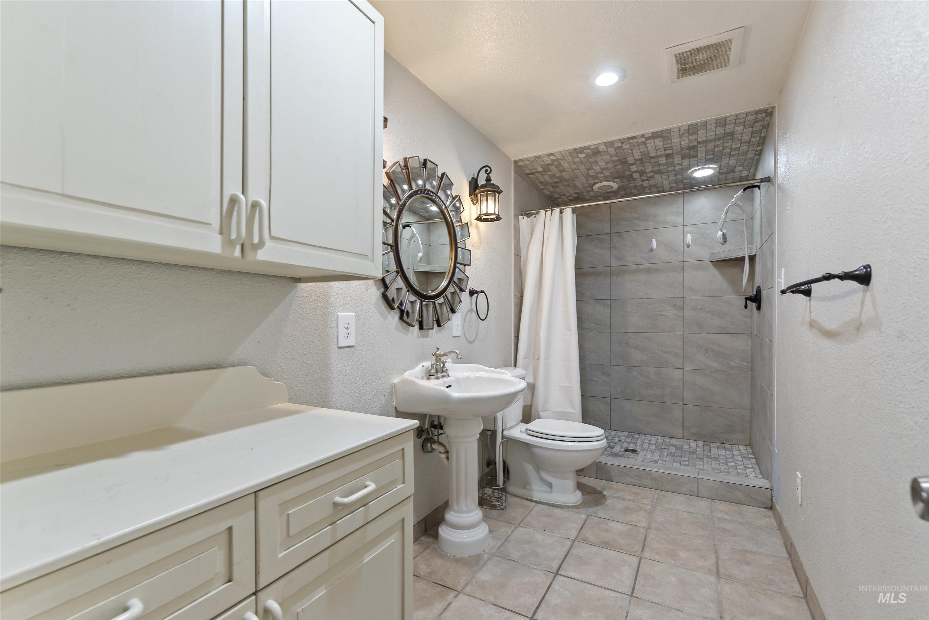 Bathroom featuring a textured wall, a stall shower, light tile patterned floors, and recessed lighting