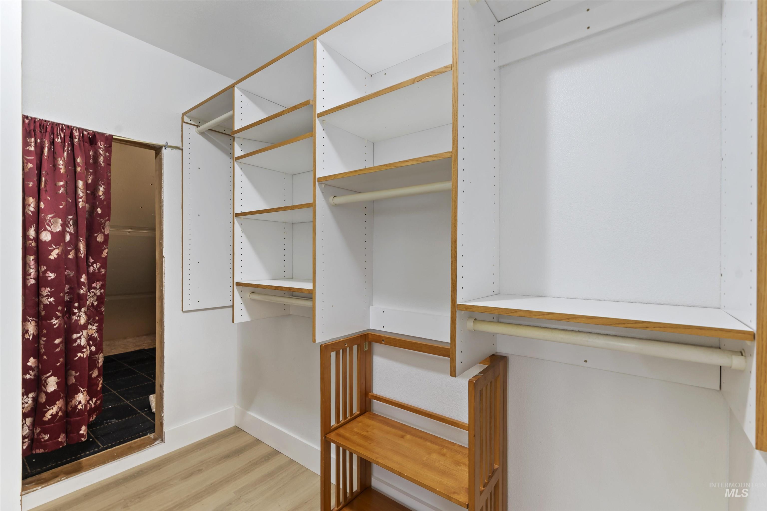 Walk in closet with light wood-style floors