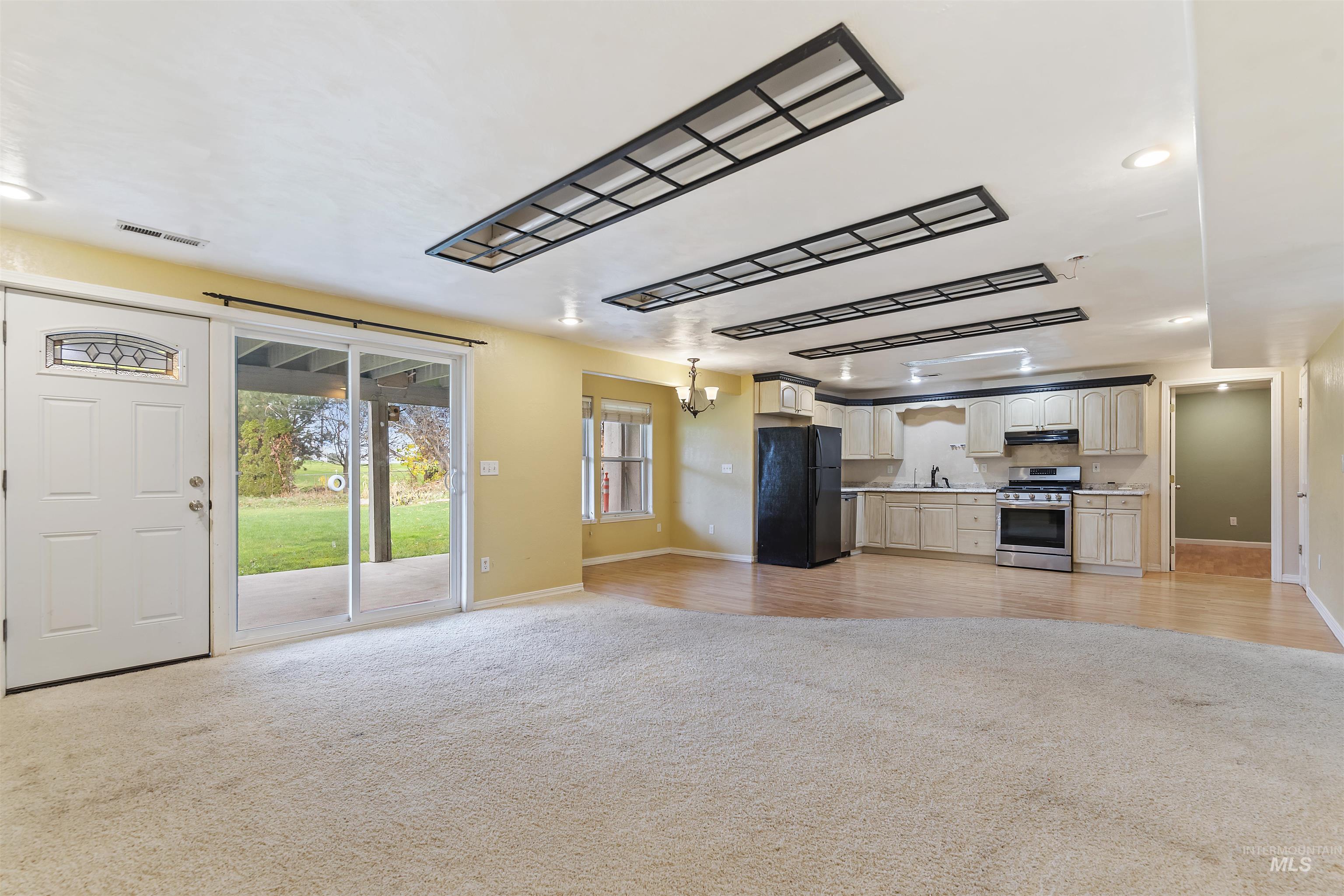 Kitchen with open floor plan, recessed lighting, stainless steel gas range, a chandelier, and freestanding refrigerator