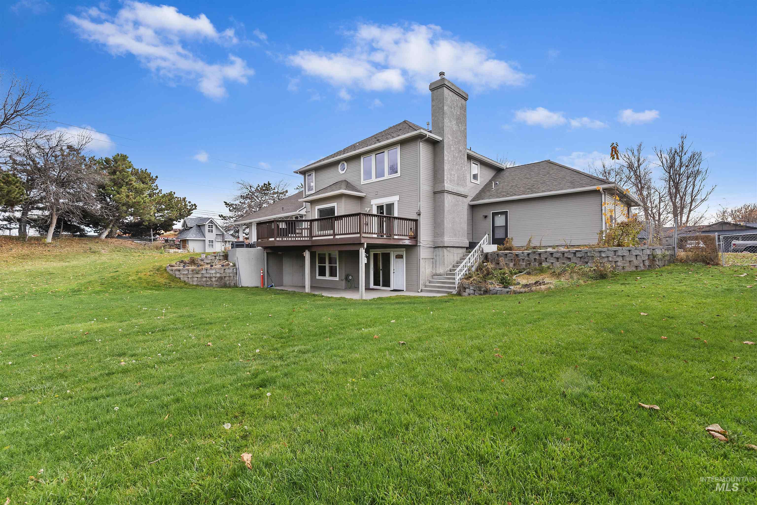 Back of house featuring a patio, stairs, a lawn, and a chimney