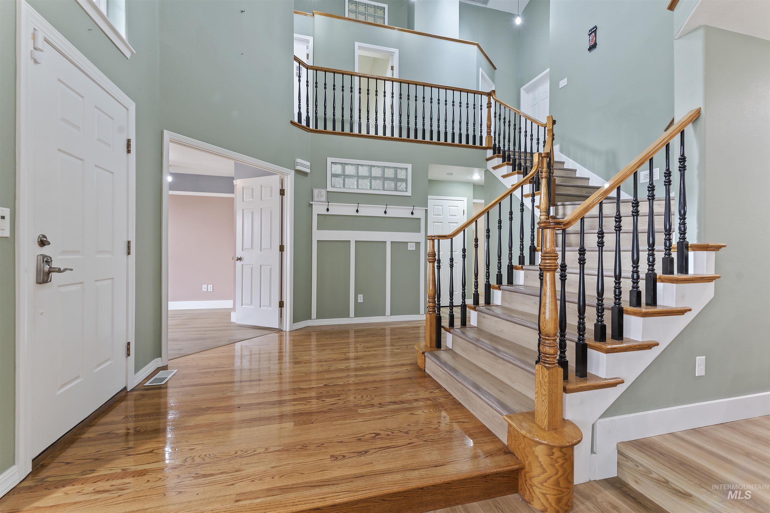 Foyer entrance with light wood-style flooring and a towering ceiling