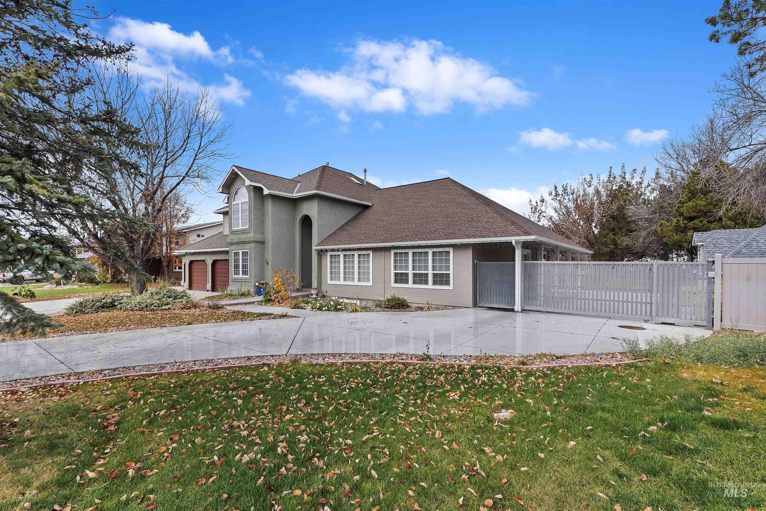 View of front of home featuring concrete driveway, a shingled roof, and a gate