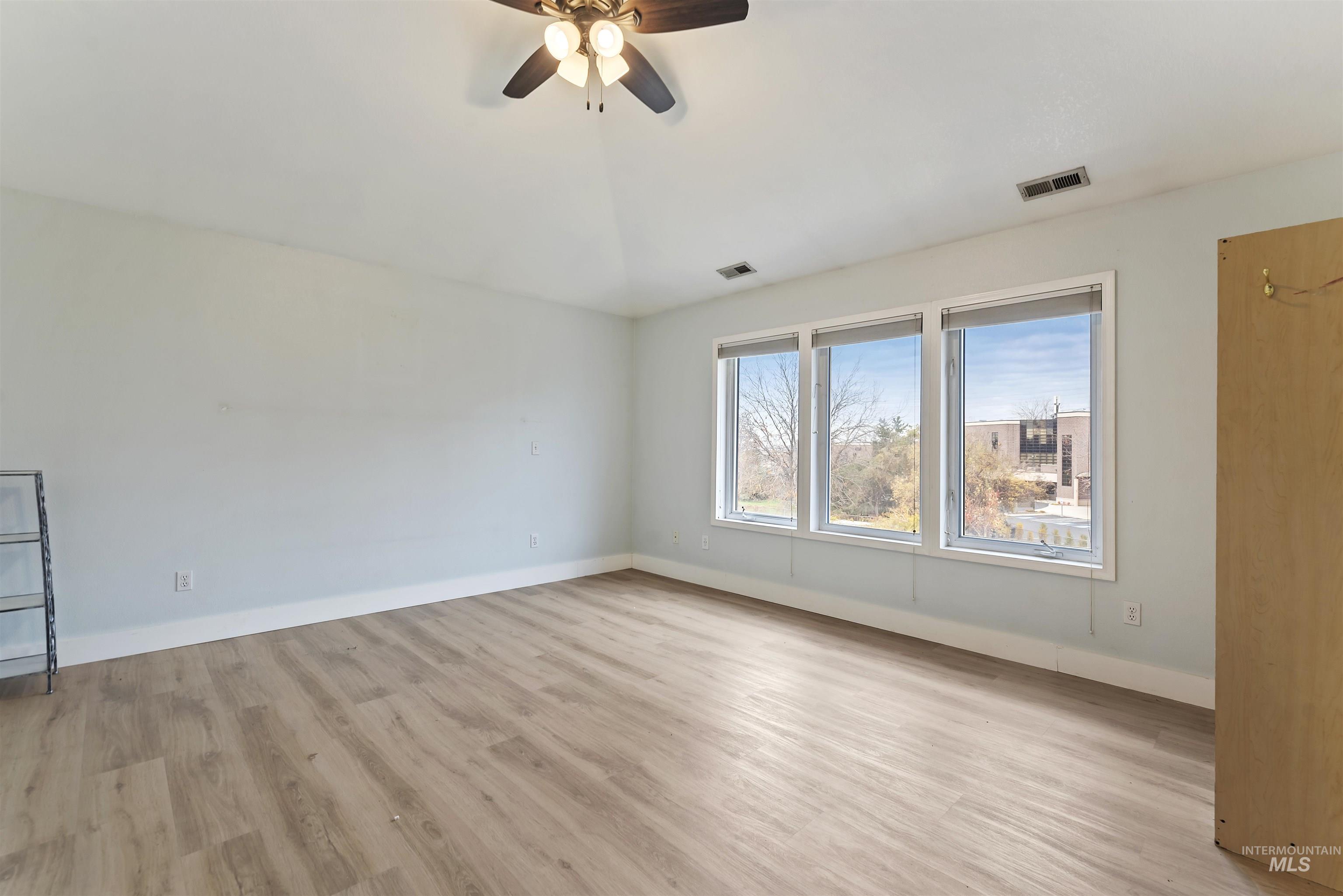 Empty room featuring light wood finished floors and a ceiling fan