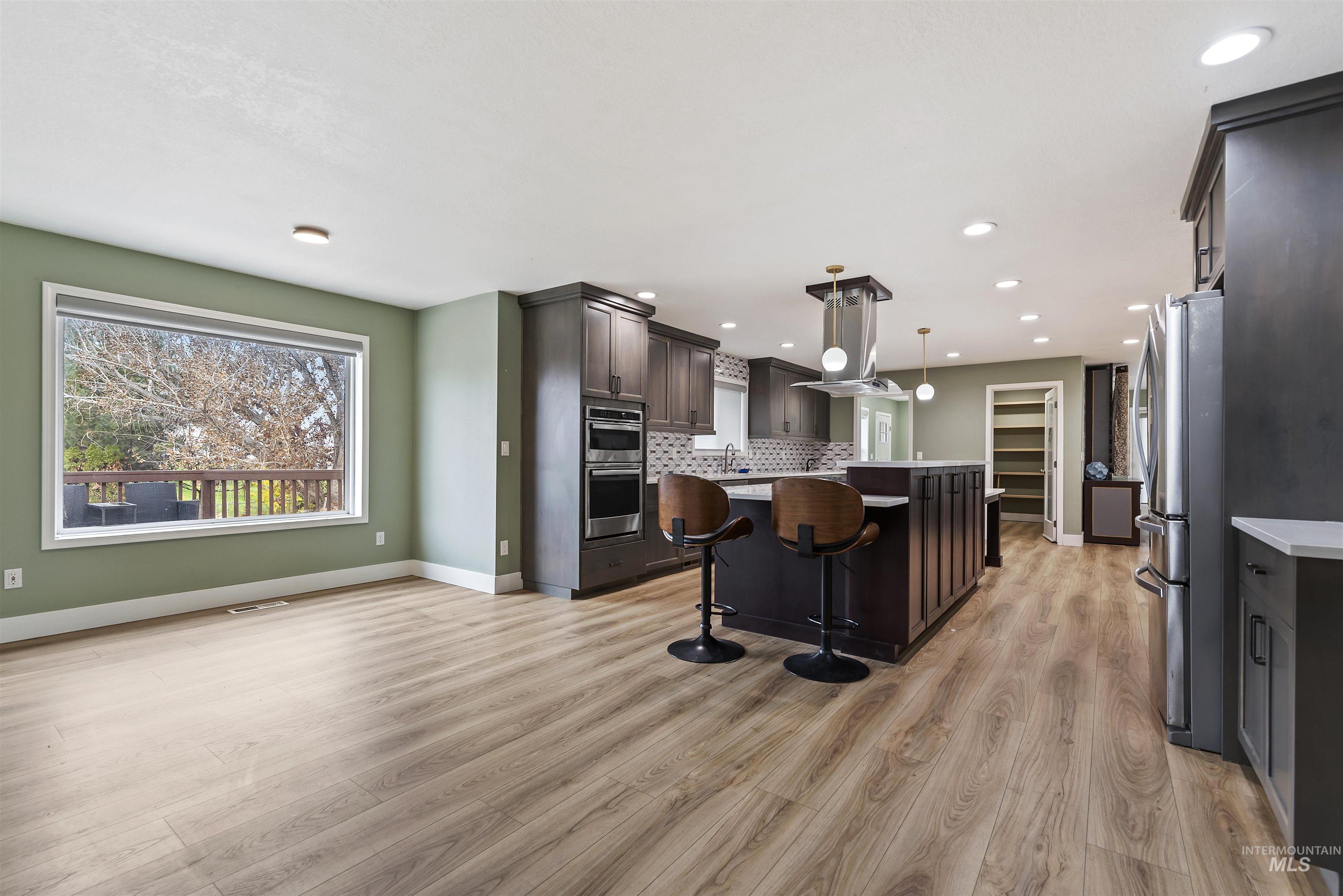 Kitchen with a kitchen bar, a kitchen island, stainless steel appliances, dark brown cabinetry, and hanging light fixtures