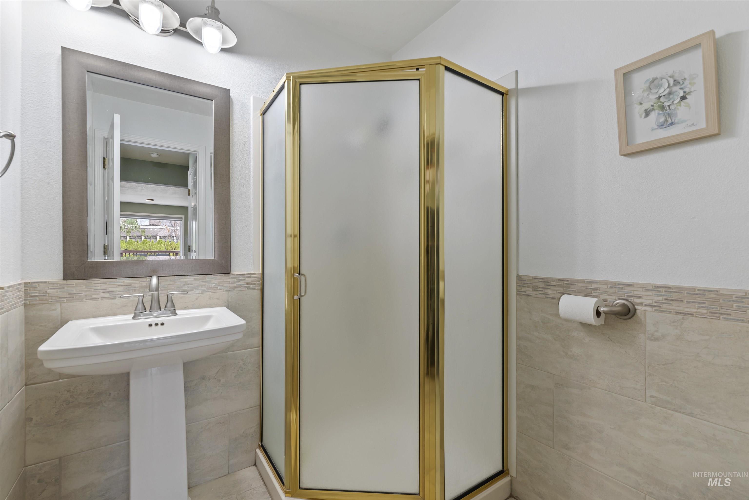 Full bath with tile walls, wainscoting, and a shower stall