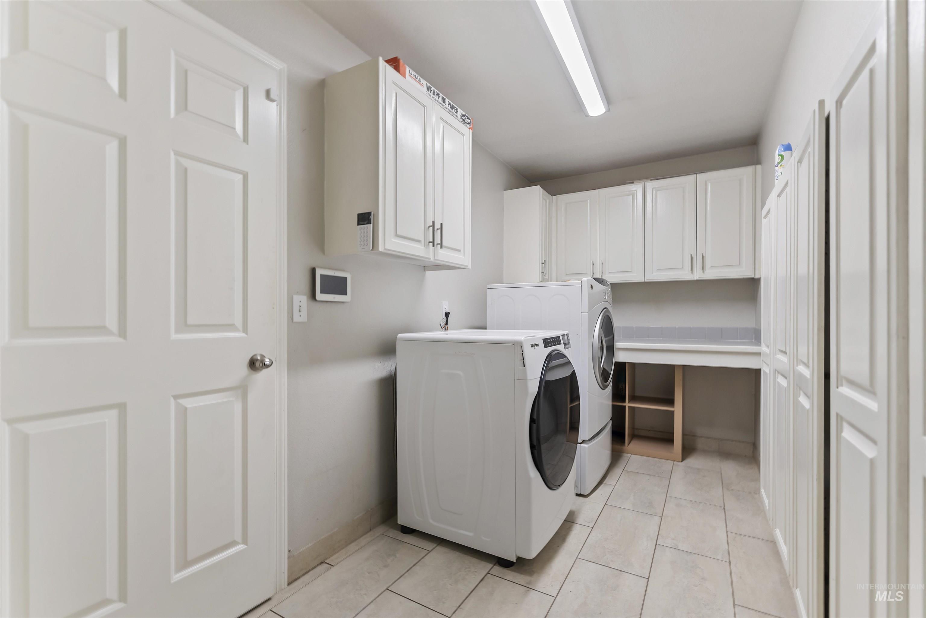 Laundry area featuring cabinet space, washer and clothes dryer, and light tile patterned floors
