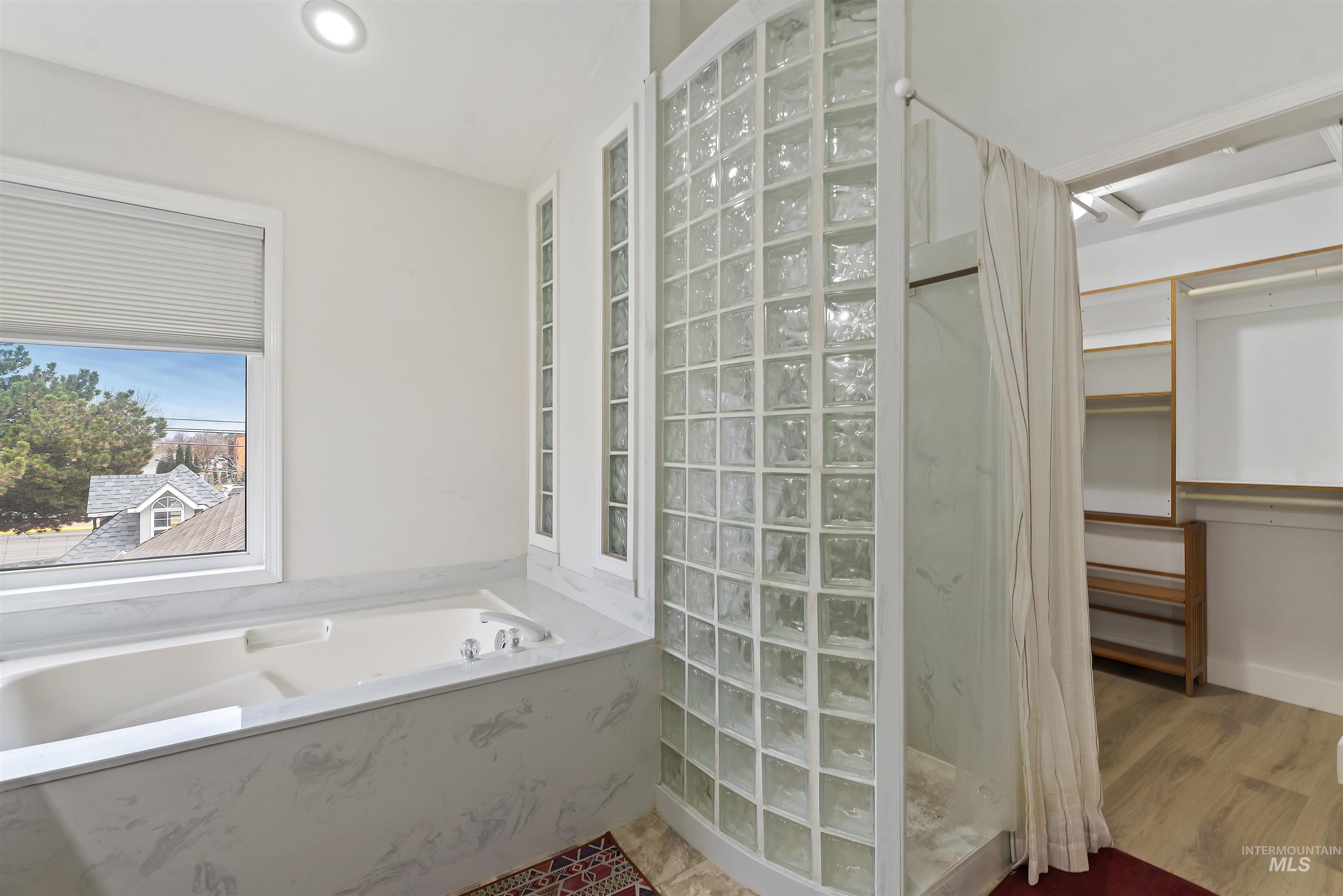 Bathroom with a marble finish shower, a garden tub, a spacious closet, and recessed lighting