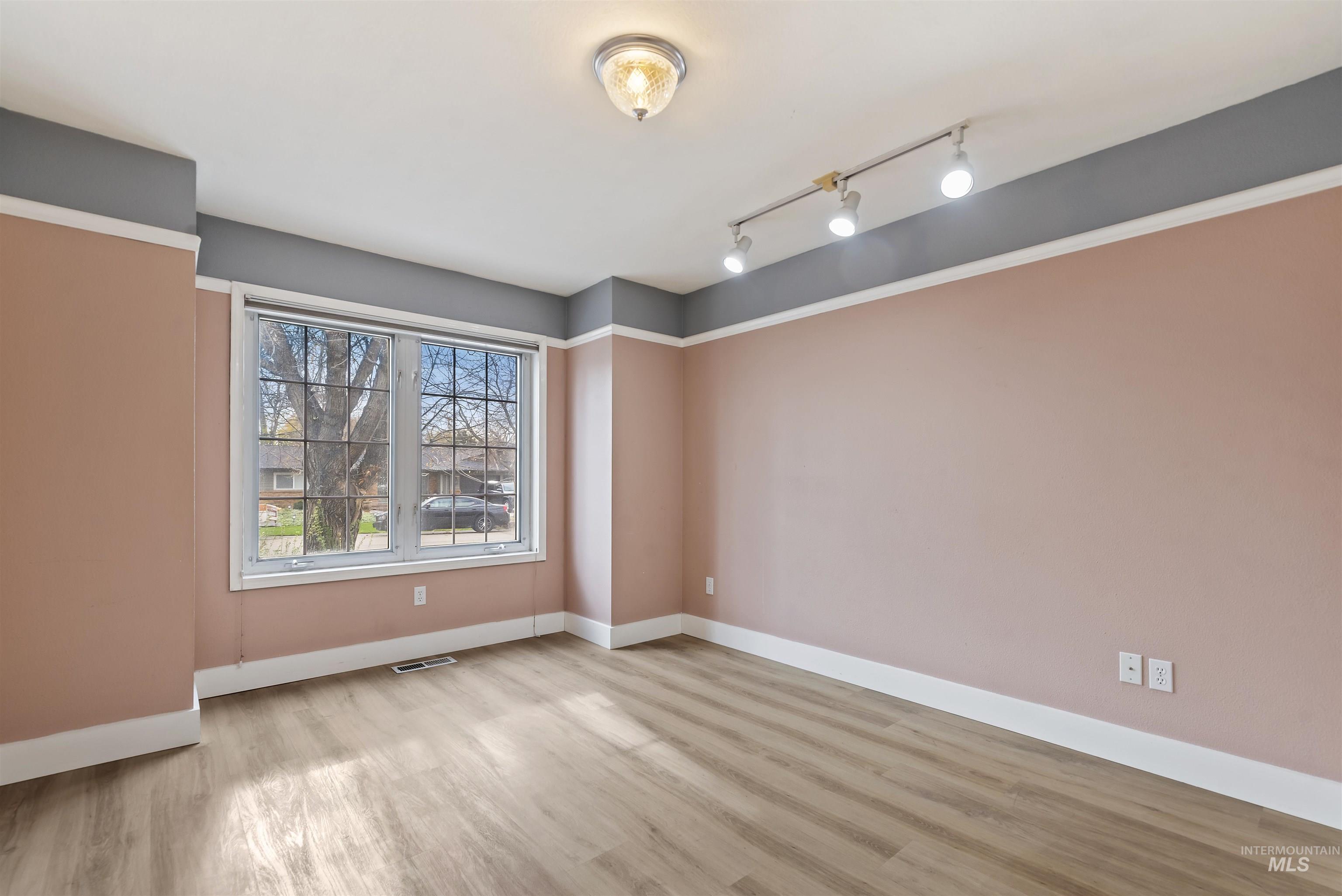 Unfurnished room featuring light wood finished floors and rail lighting