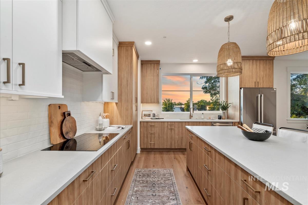 Kitchen with light wood-type flooring, decorative light fixtures, modern cabinets, plenty of natural light, and recessed lighting