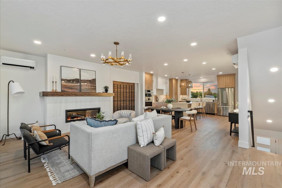 Living room with recessed lighting, a tile fireplace, light wood finished floors, an AC wall unit, and a chandelier