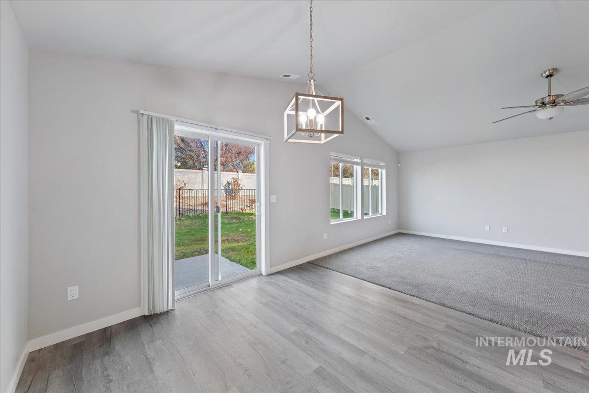 Unfurnished dining area featuring vaulted ceiling, a chandelier, light wood-style floors, and ceiling fan
