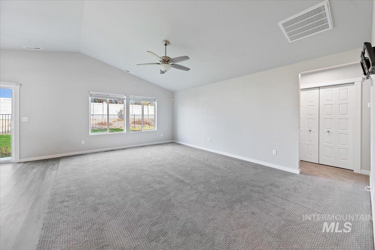 Unfurnished living room with vaulted ceiling and ceiling fan