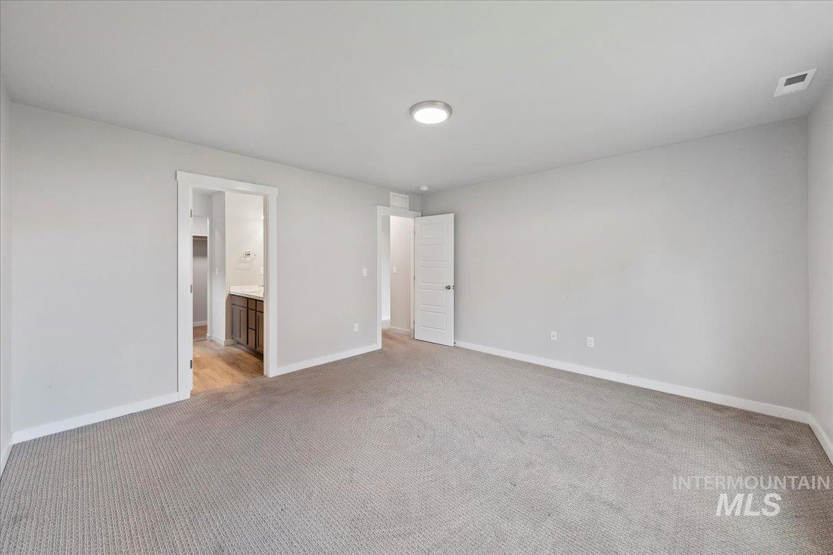 Unfurnished bedroom featuring ensuite bath and light carpet