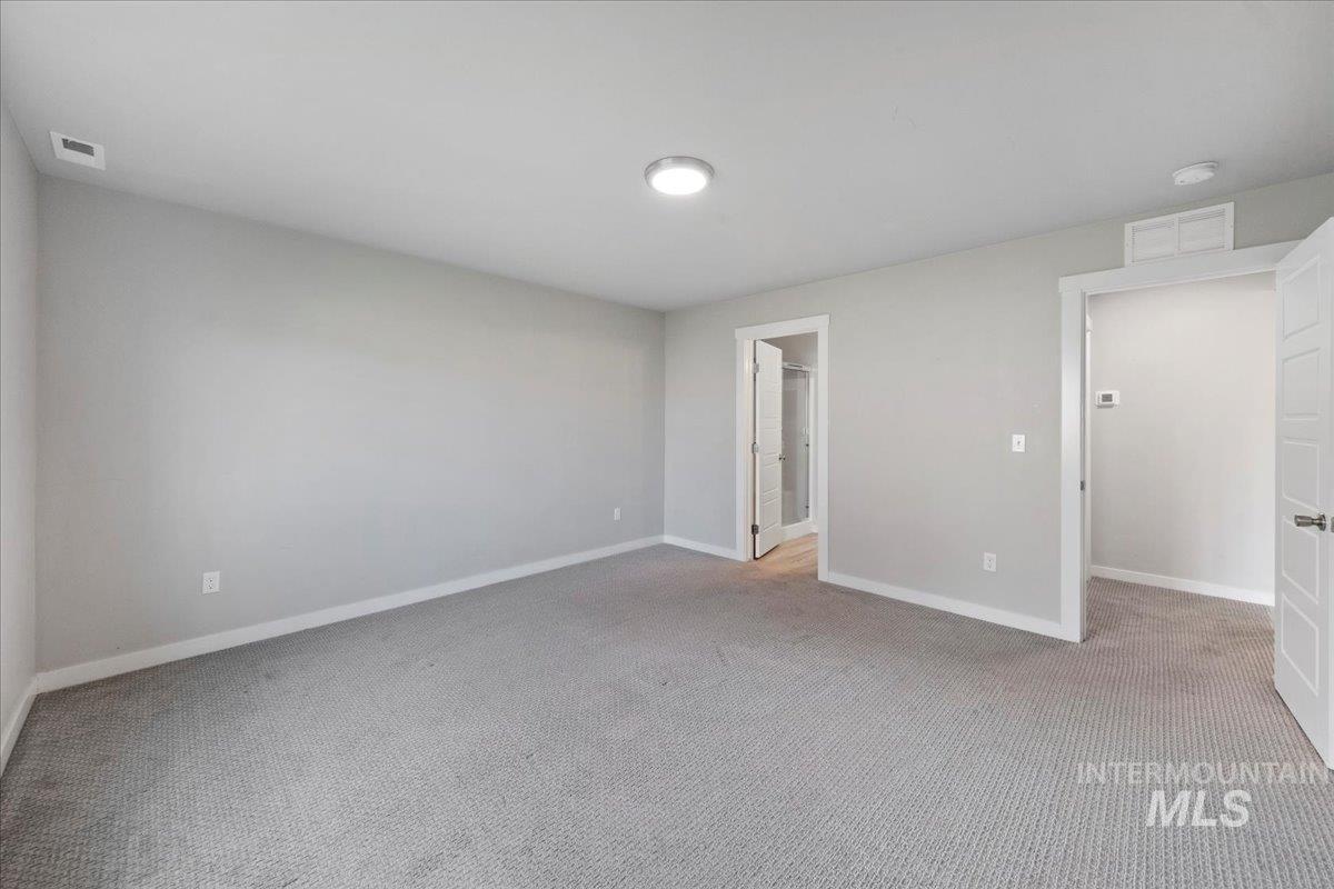 Unfurnished bedroom with light colored carpet and ensuite bathroom