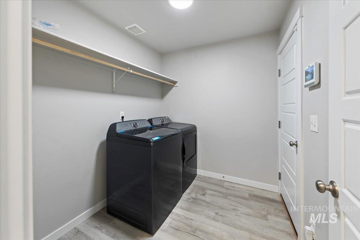 Laundry area with light wood-style flooring and independent washer and dryer