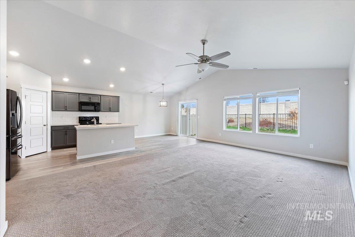 Unfurnished living room featuring vaulted ceiling, light carpet, a ceiling fan, and recessed lighting