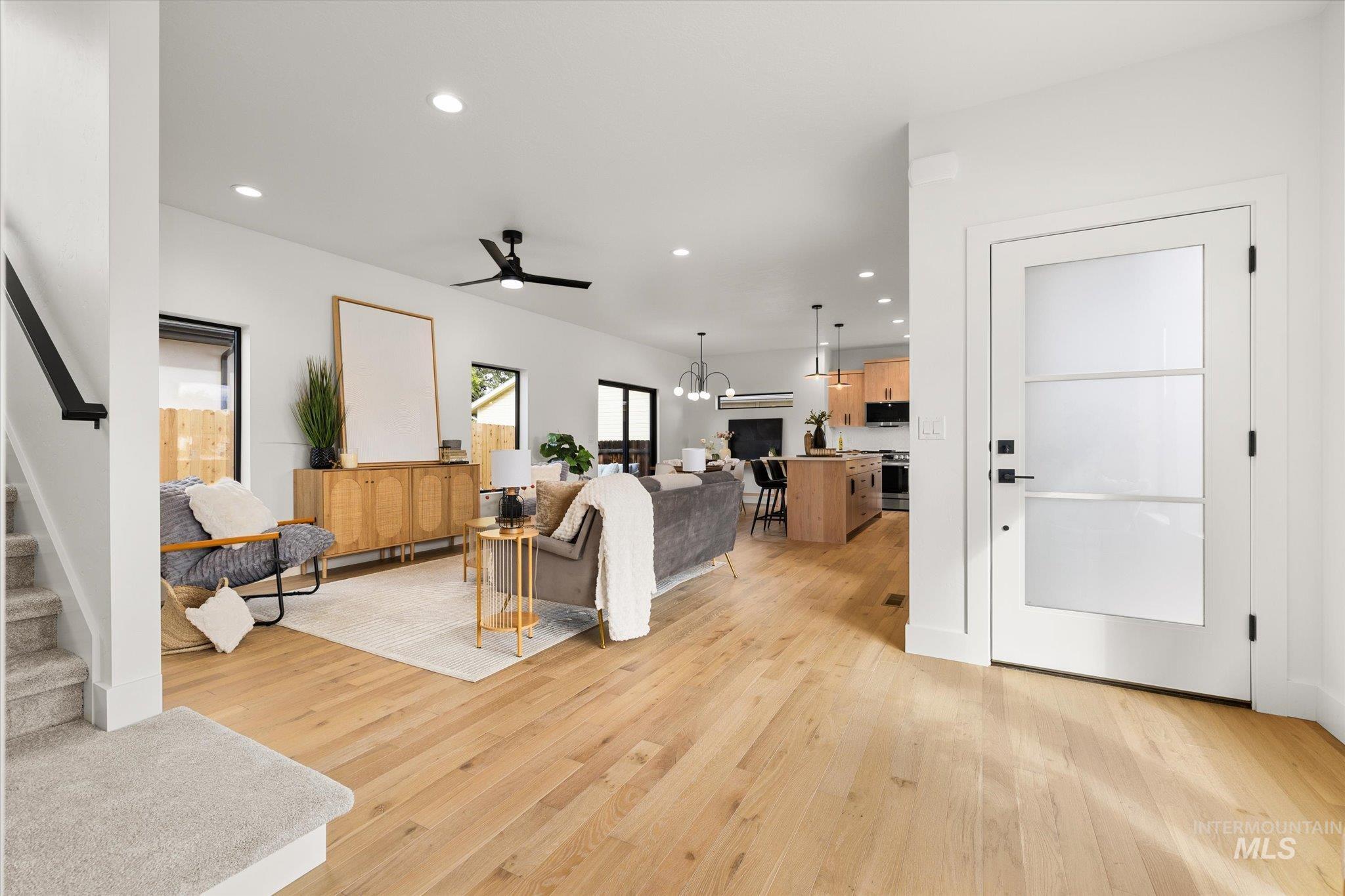 Living area with stairway, a chandelier, recessed lighting, light wood-style floors, and a ceiling fan