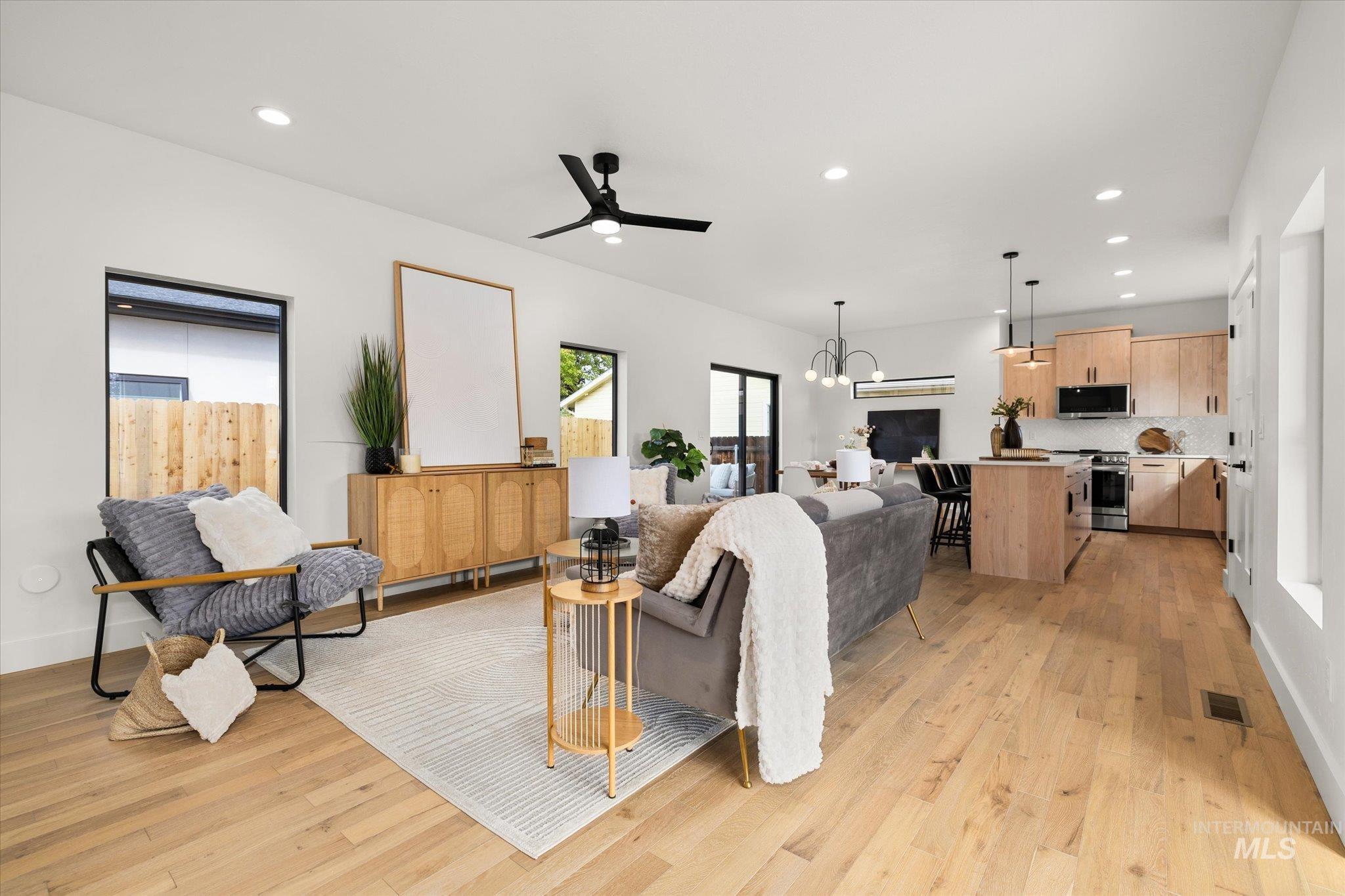 Living room with recessed lighting, light wood-style floors, a chandelier, and a ceiling fan