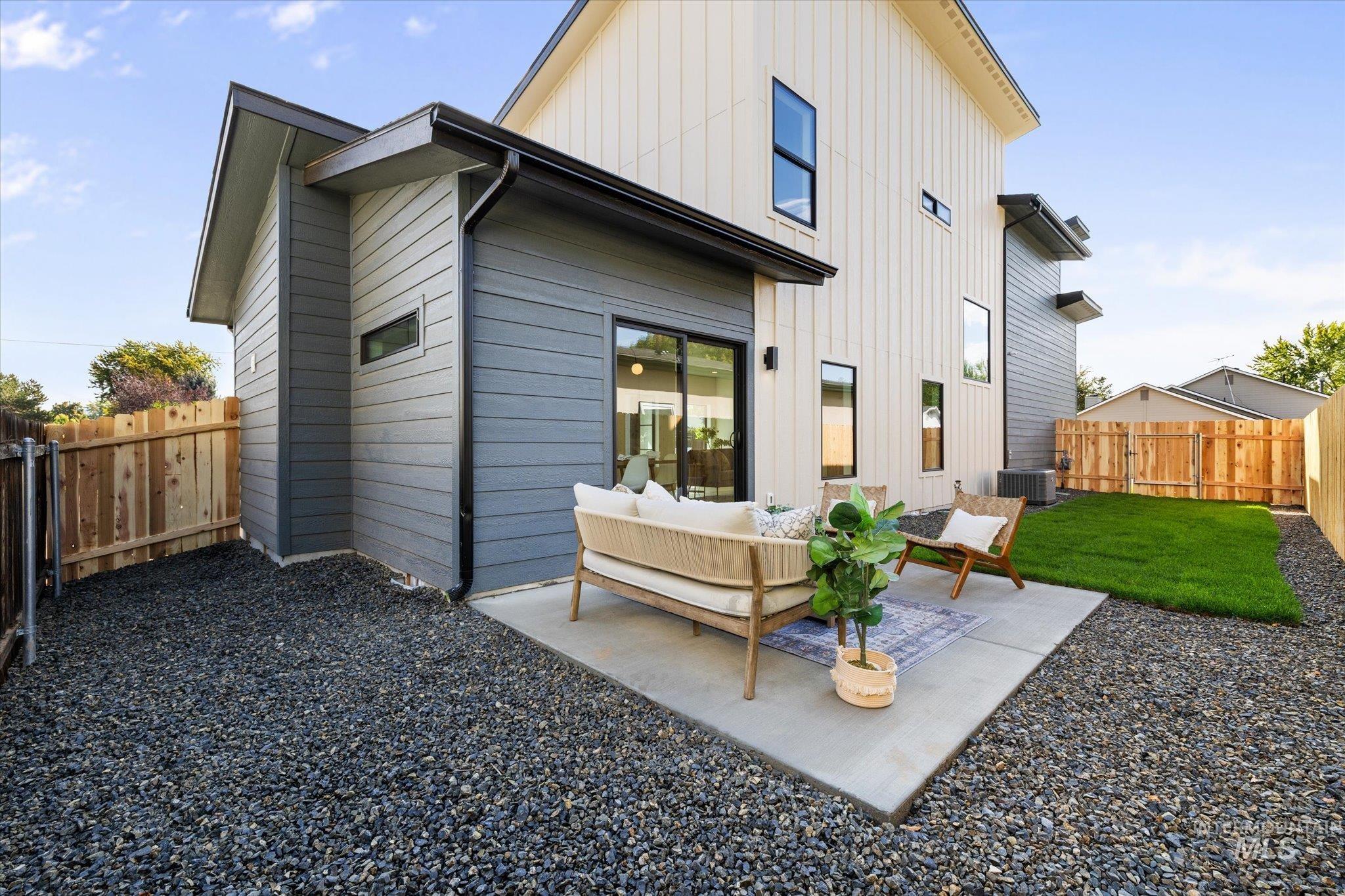 Rear view of house with a fenced backyard, a patio area, board and batten siding, and an outdoor living space