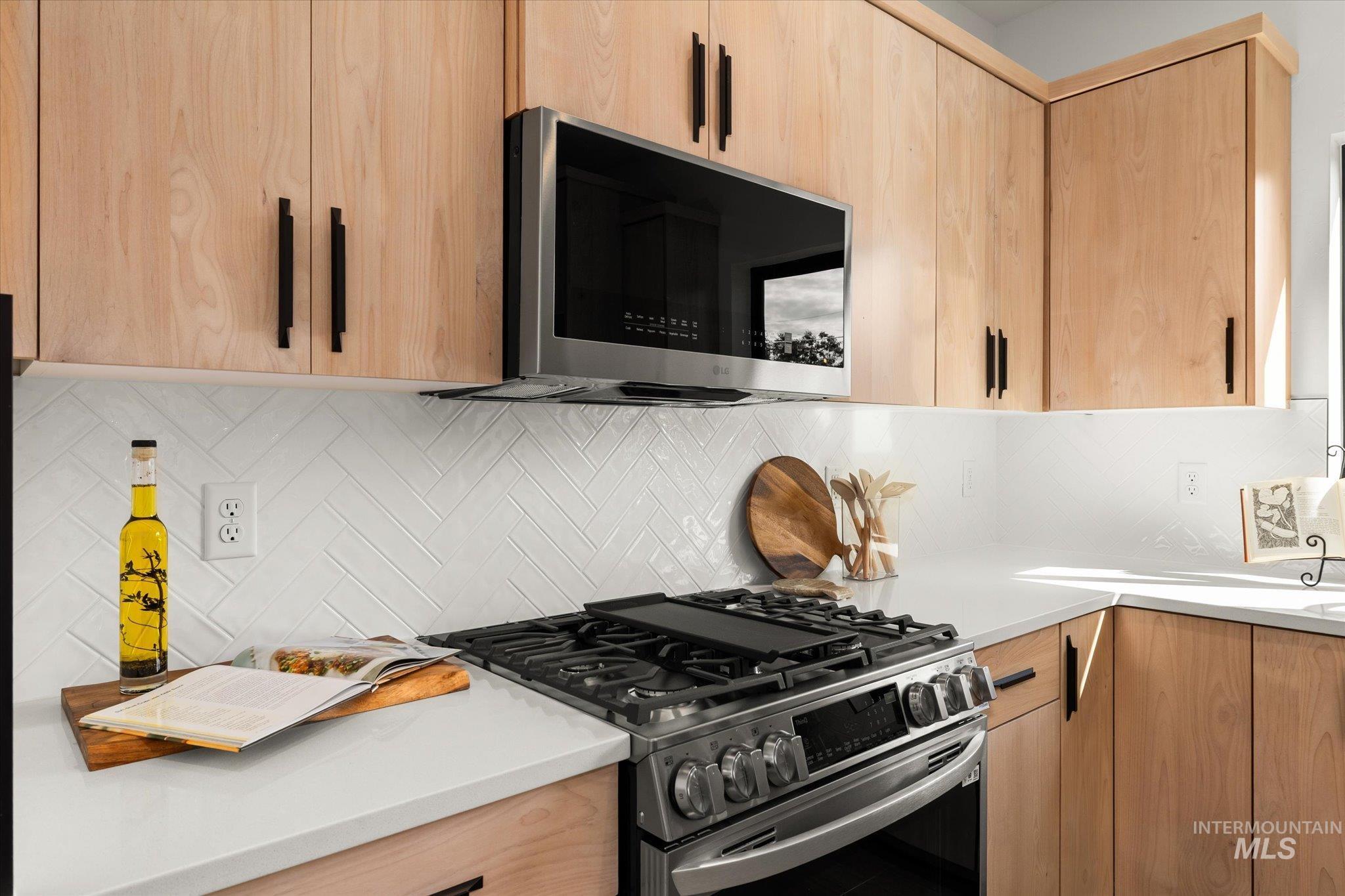 Kitchen with light brown cabinetry, stainless steel appliances, backsplash, and modern cabinets