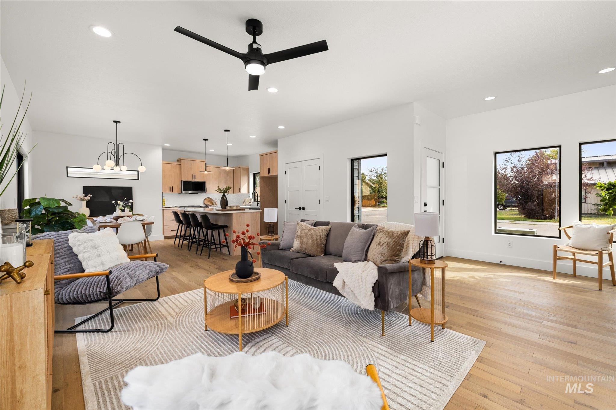 Living room featuring recessed lighting, light wood-type flooring, ceiling fan, and a chandelier