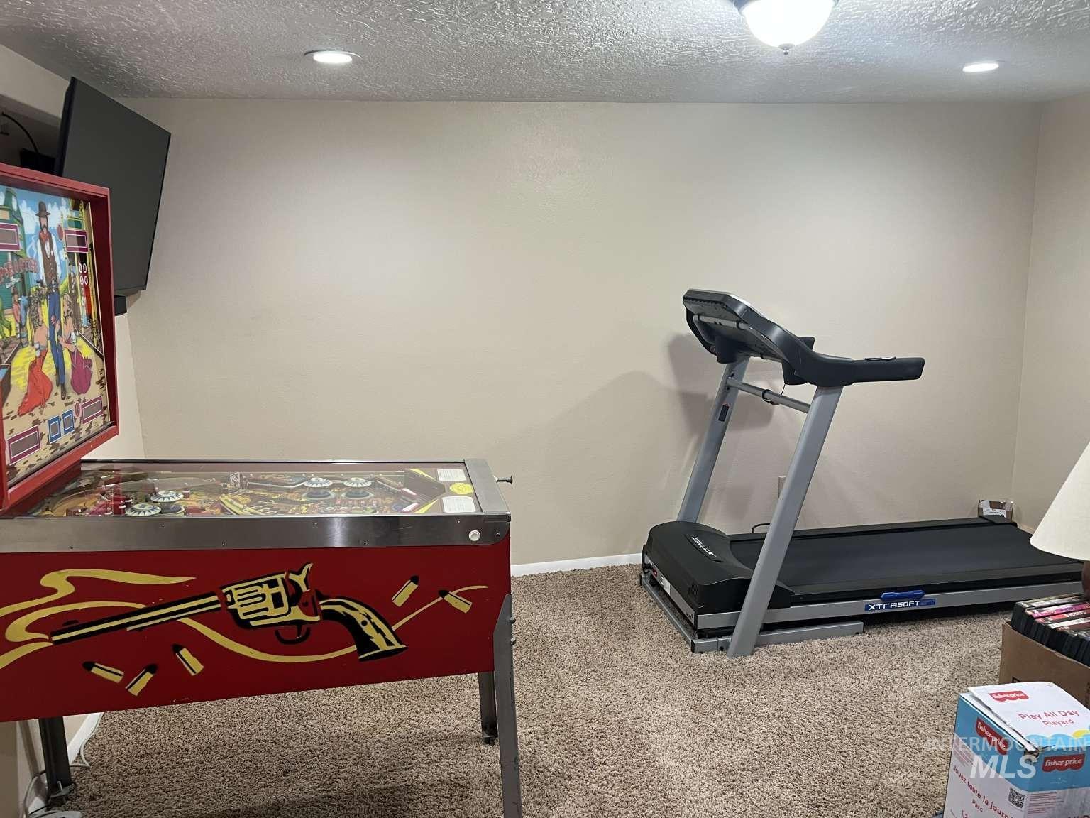 Exercise area with a textured ceiling, carpet, and recessed lighting