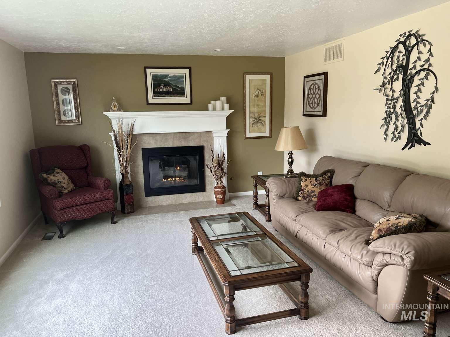 Carpeted living area with a textured ceiling and a tiled fireplace