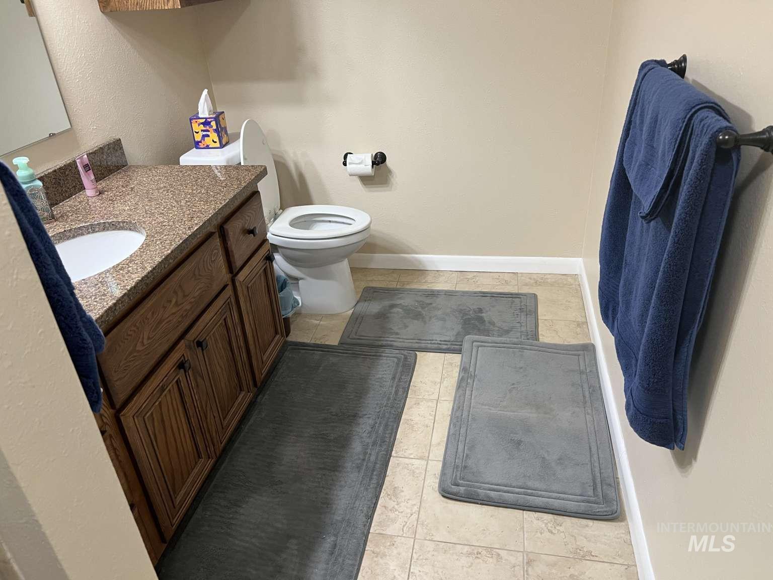 Half bath featuring light tile patterned flooring, vanity, and a textured wall