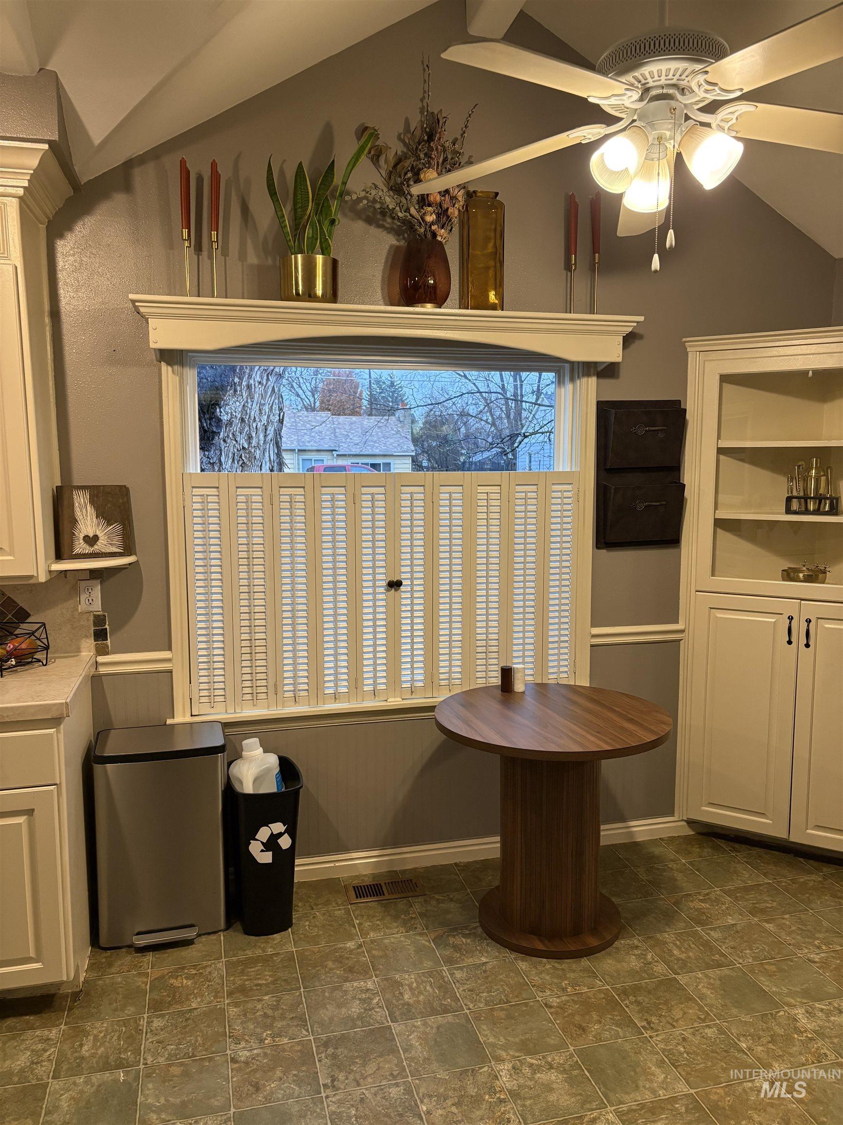 Dining area featuring ceiling fan, vaulted ceiling, and stone finish floors