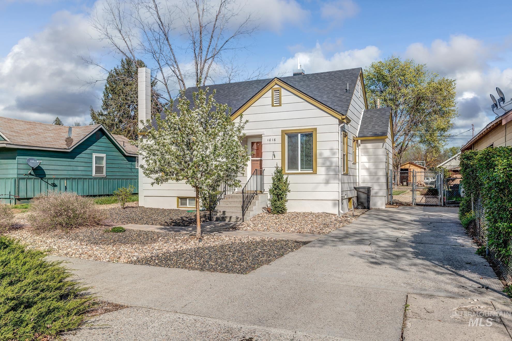 Bungalow featuring a shingled roof, a gate, a chimney, and driveway