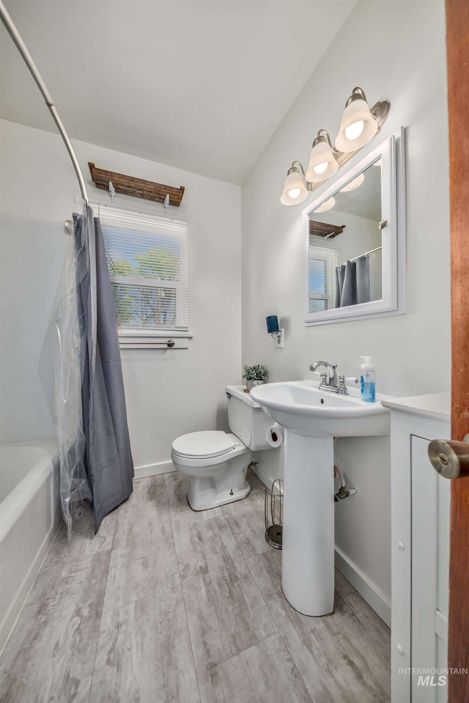 Bathroom with light wood finished floors and shower / tub combo