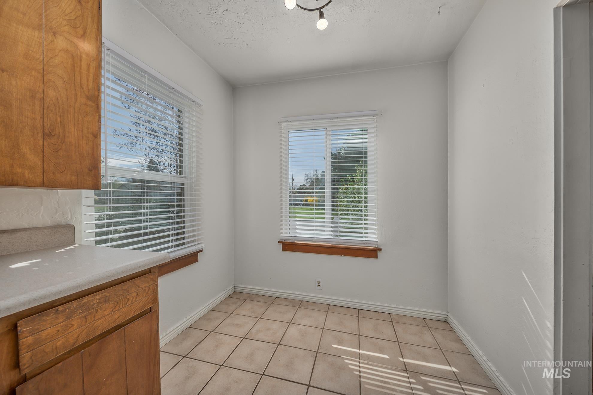 Unfurnished dining area featuring light tile patterned floors and a textured ceiling