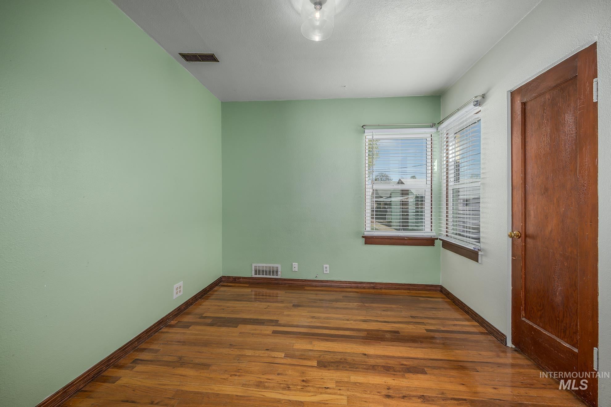 Unfurnished bedroom featuring dark wood-style flooring and baseboards