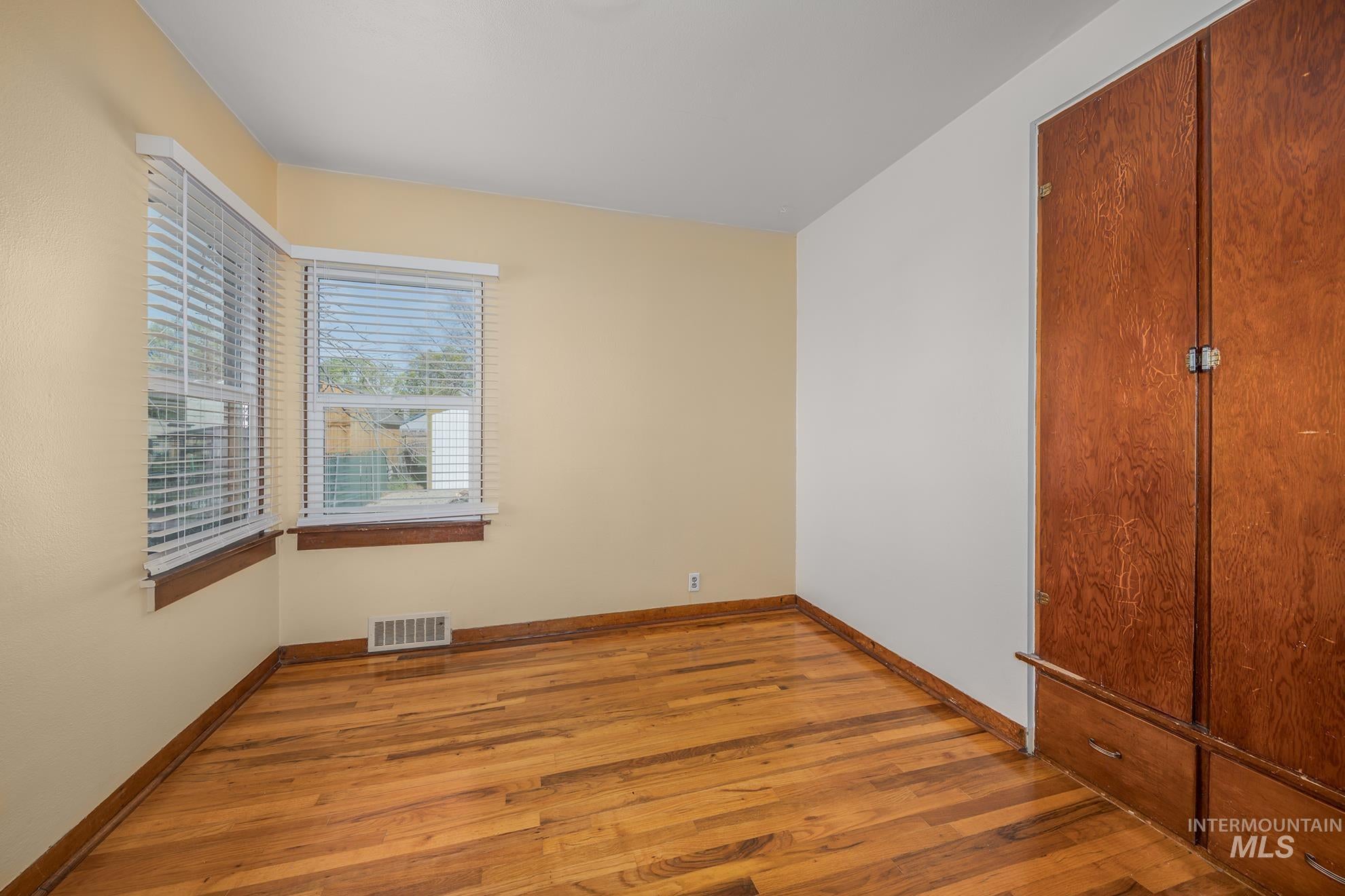 Unfurnished bedroom with wood-type flooring and baseboards