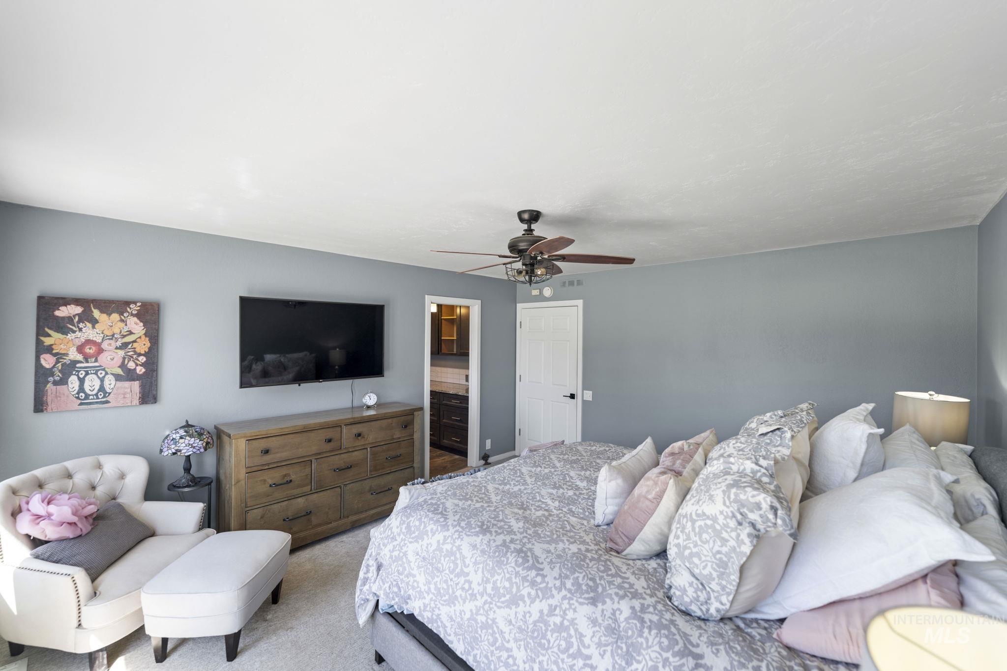 Carpeted bedroom featuring a ceiling fan and ensuite bathroom