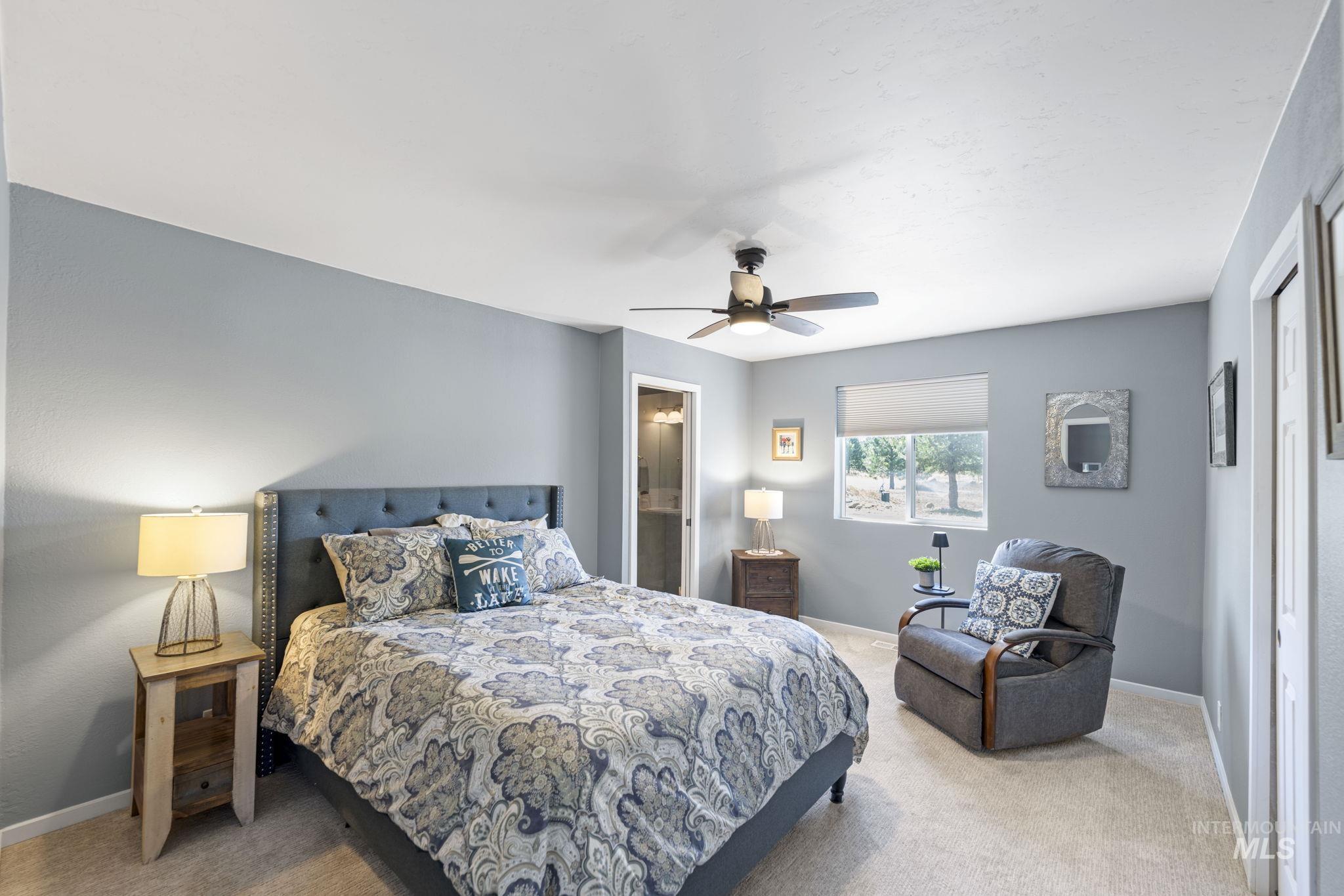 Bedroom with light carpet, ceiling fan, and ensuite bathroom