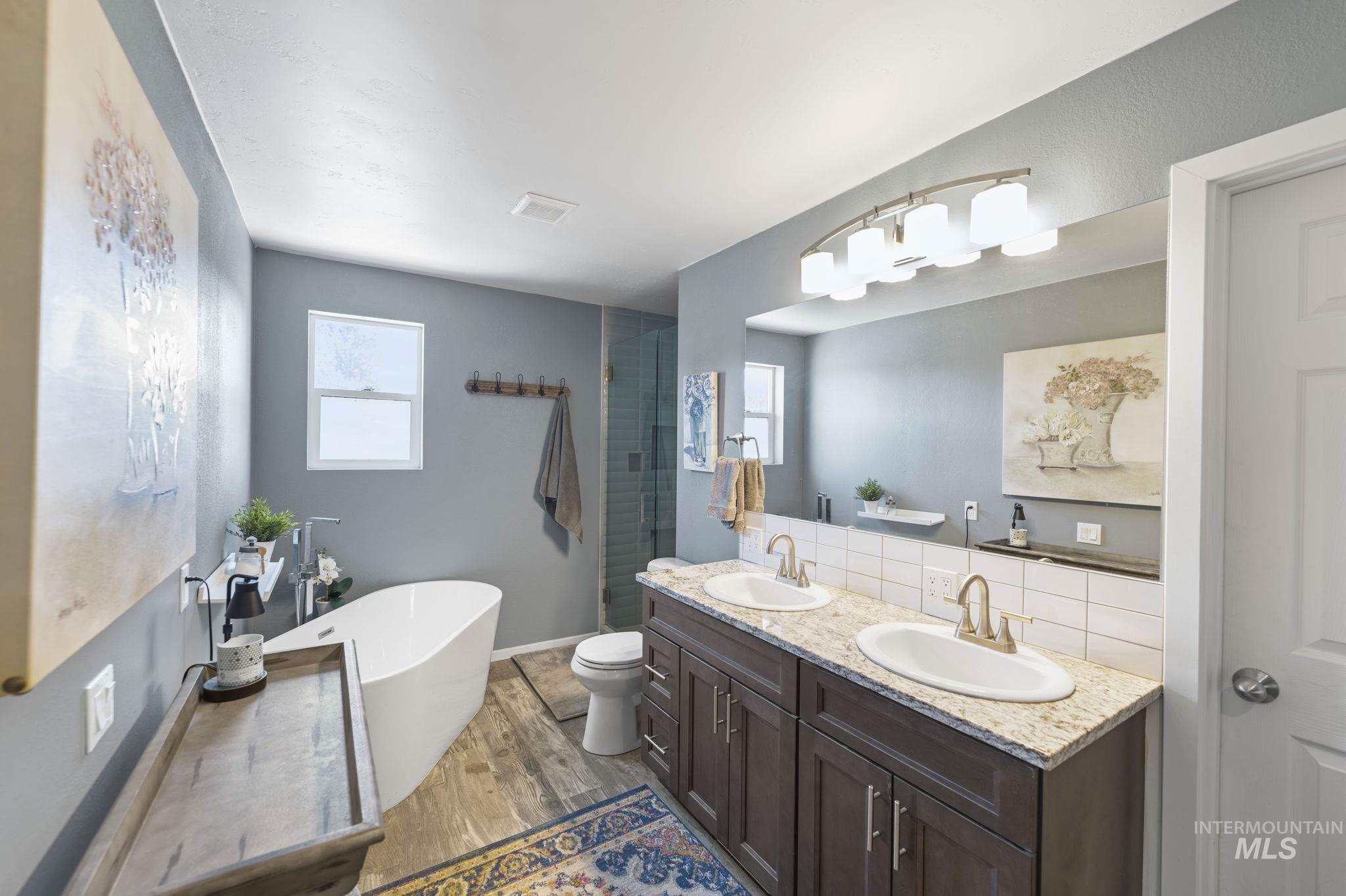 Bathroom with a soaking tub, plenty of natural light, light wood finished floors, and double vanity