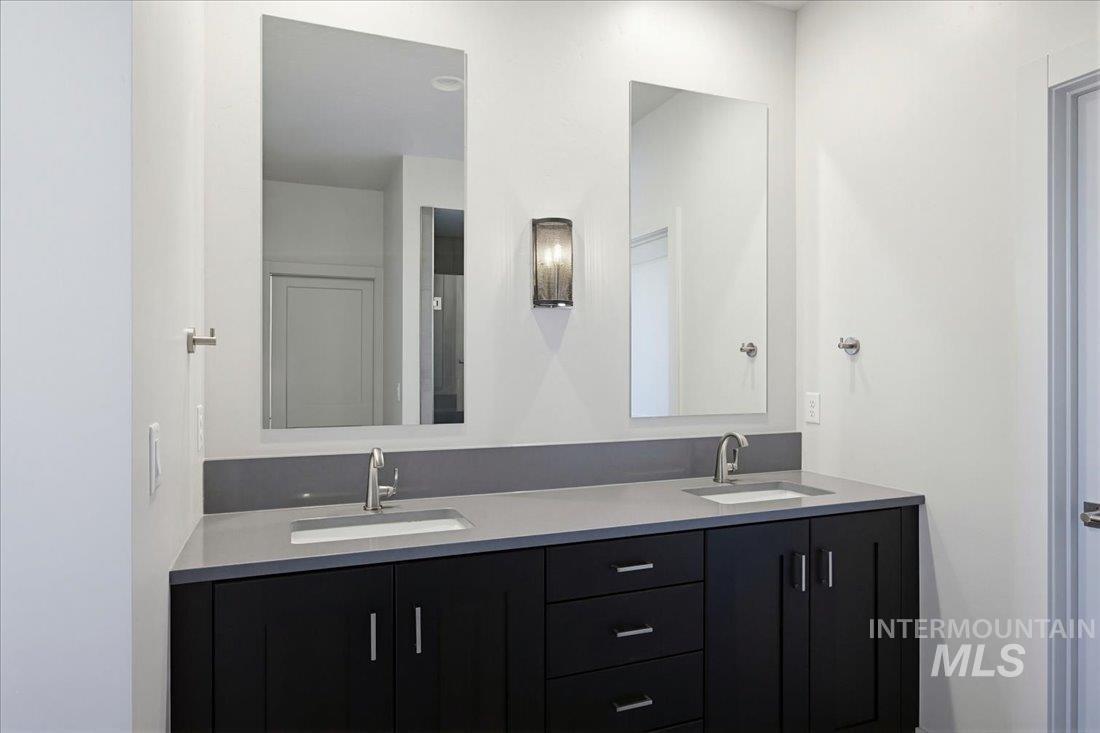 Dual vanity featuring a light gray countertop, undermount sinks, and matte black shaker-style cabinetry with chrome hardware