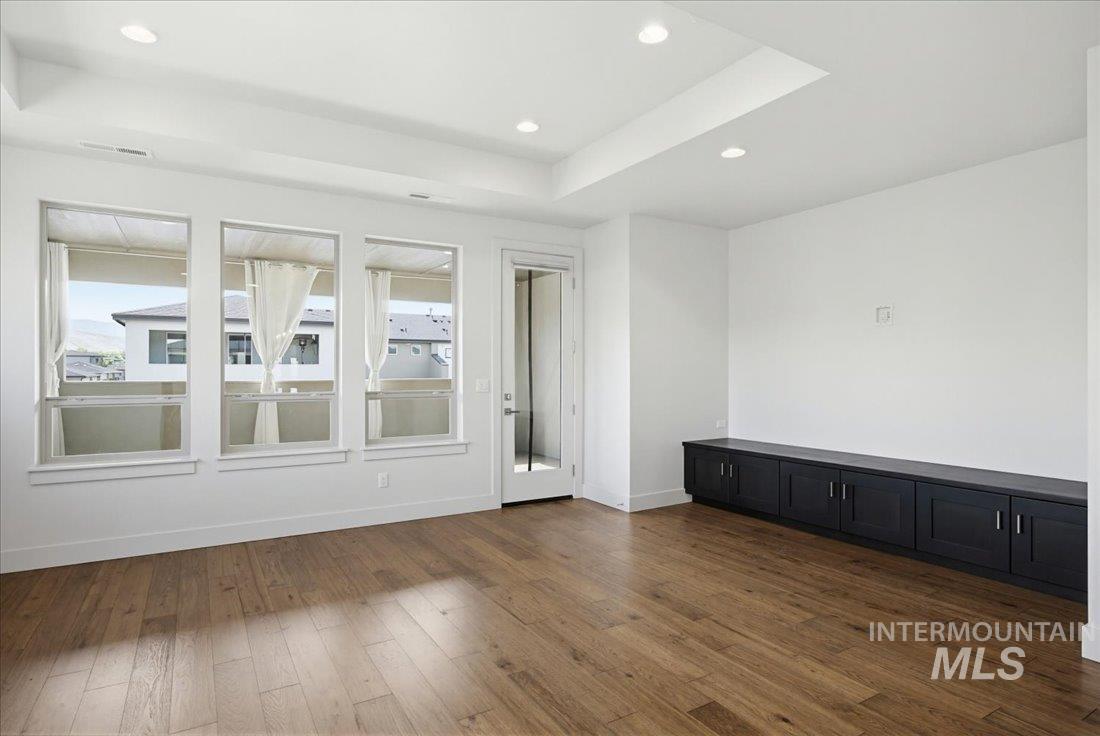 Open living space featuring wood-finish flooring, recessed lighting, and a tray ceiling