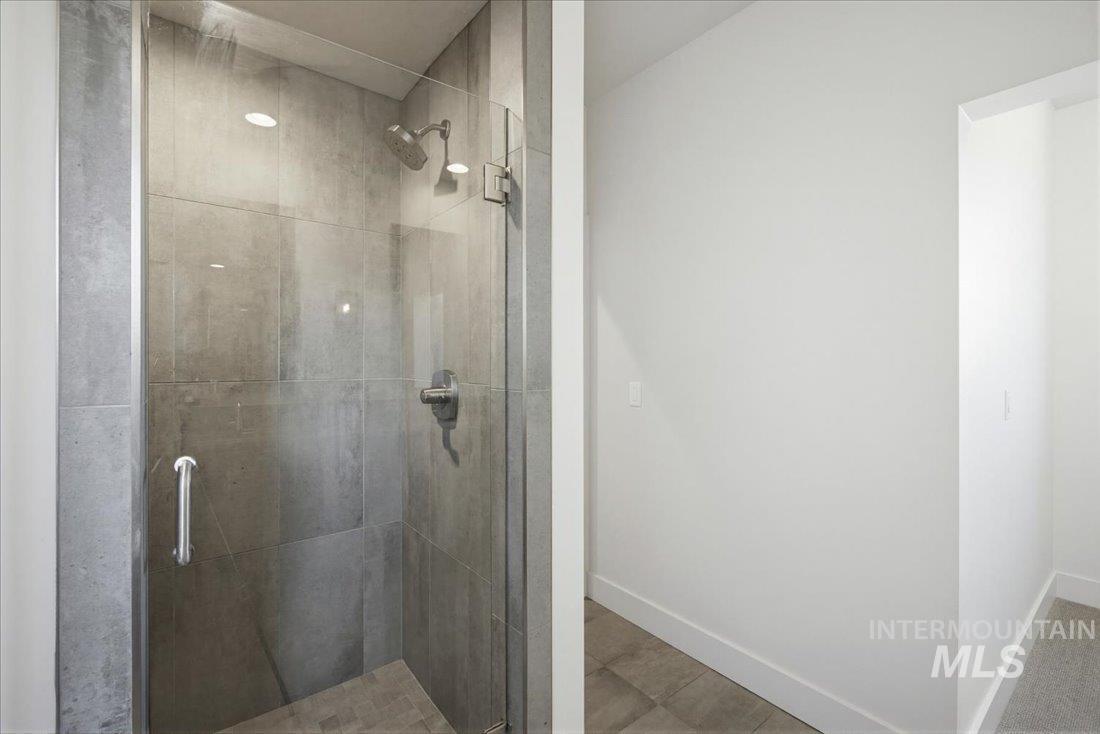 Walk-in shower with full-height tile surround, frameless glass enclosure, recessed lighting, and a rainfall showerhead