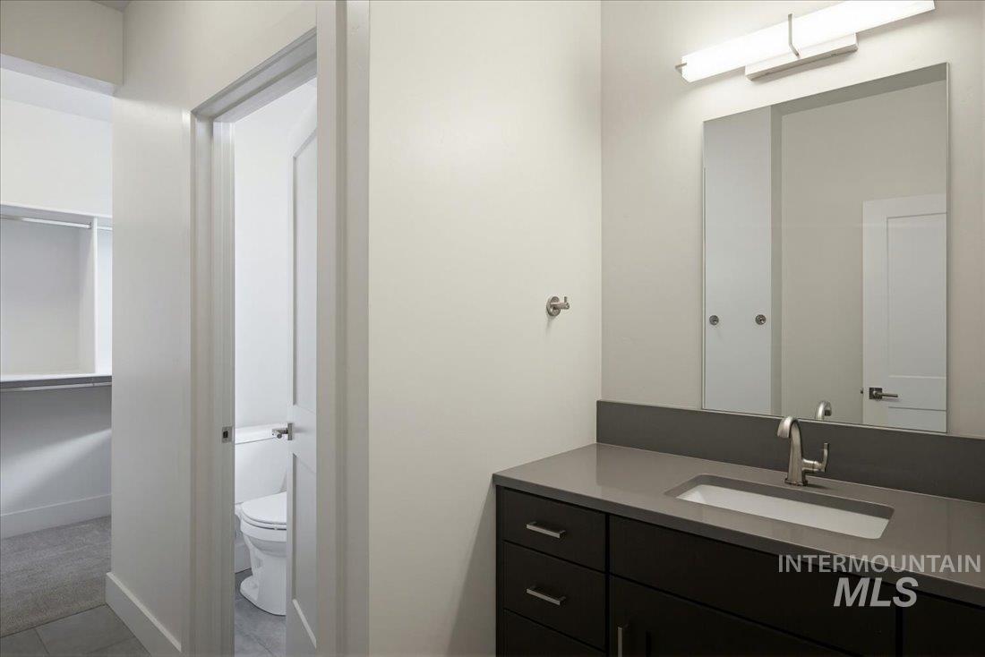 Bathroom vanity featuring a rectangular undermount sink, a gray countertop, and dark wood cabinetry with brushed nickel hardware