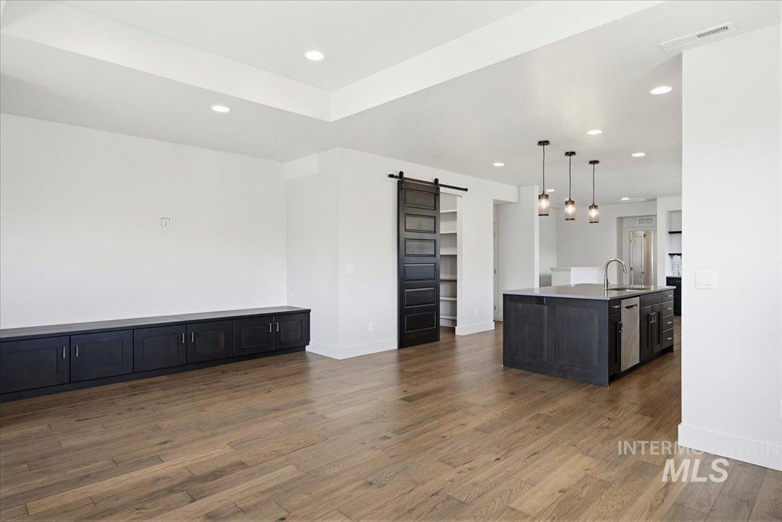 Expansive open-concept living space featuring wood-finish flooring, recessed lighting, and a tray ceiling