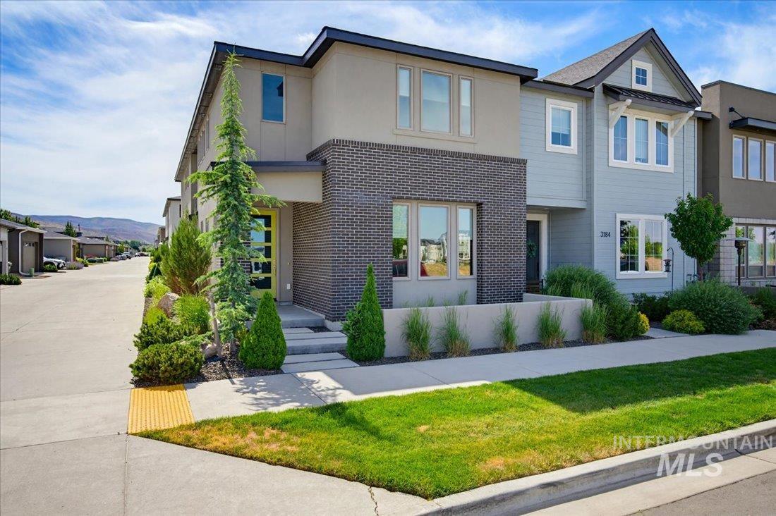 Contemporary exterior featuring a brick accent wall, light stucco, and a striking yellow-framed front door