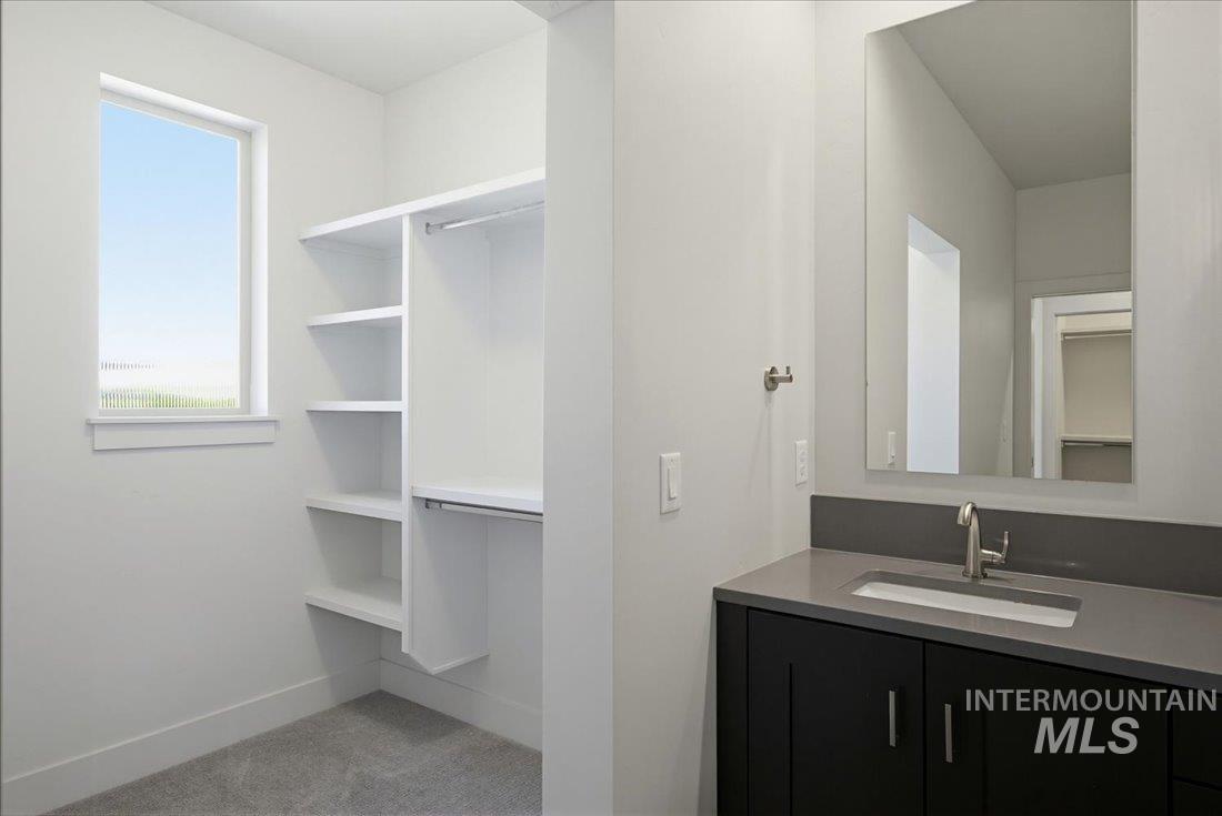 Walk-in closet with built-in shelving, hanging rods, and a window