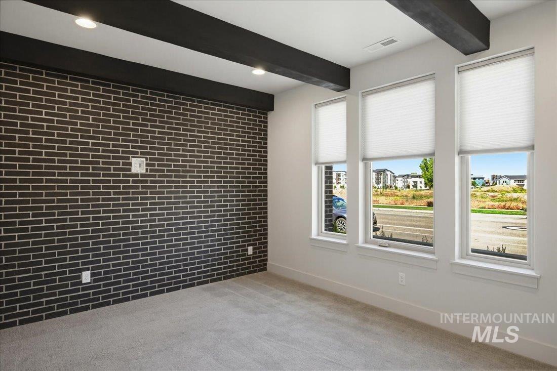 Accent wall featuring dark brick-finish detailing, recessed lighting, and exposed ceiling beams