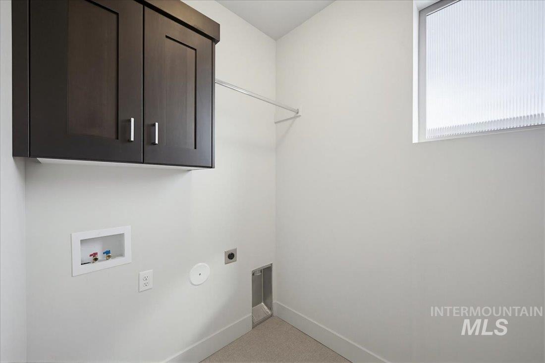 Dedicated laundry area featuring dark wood-finish cabinetry with brushed nickel hardware, a window with horizontal blinds, and a built-in hanging rod