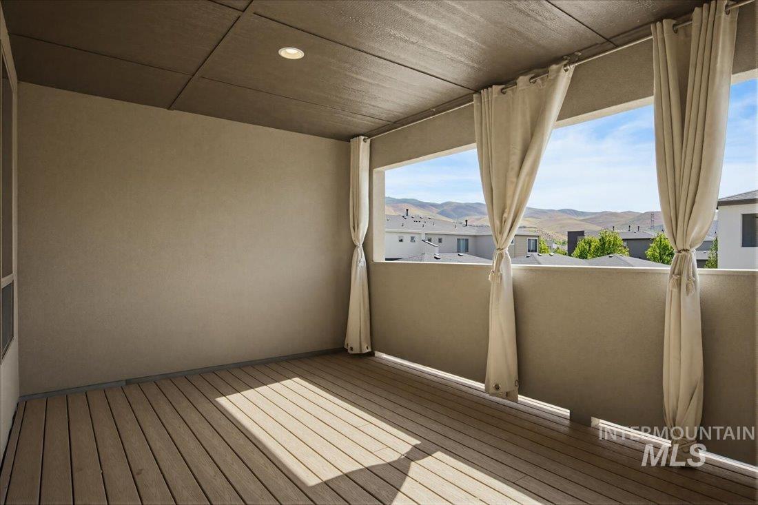 Covered outdoor balcony featuring wood-finish flooring, stucco walls, and a recessed ceiling light