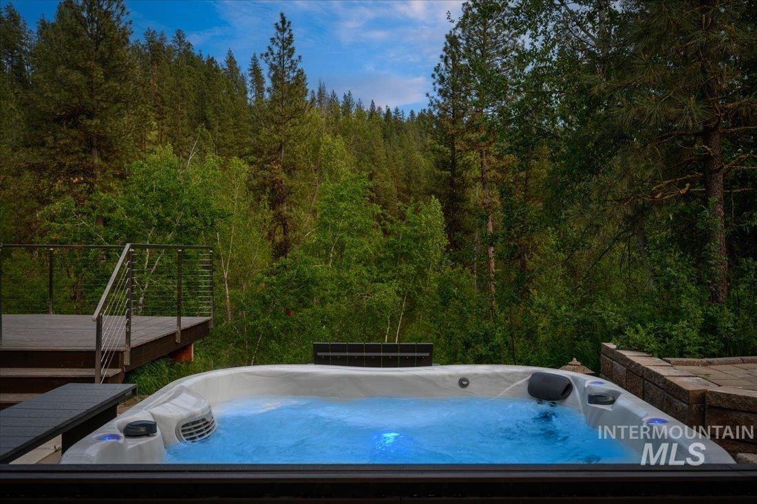 Wooden terrace featuring a hot tub and a view of trees