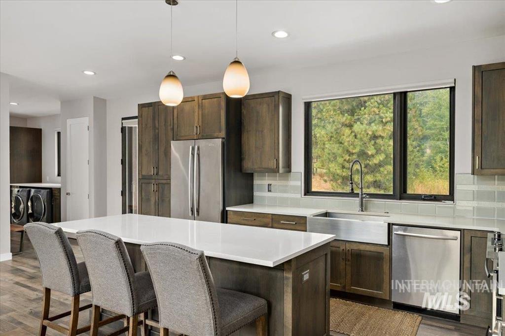 Kitchen featuring recessed lighting, appliances with stainless steel finishes, pendant lighting, decorative backsplash, and washer and dryer