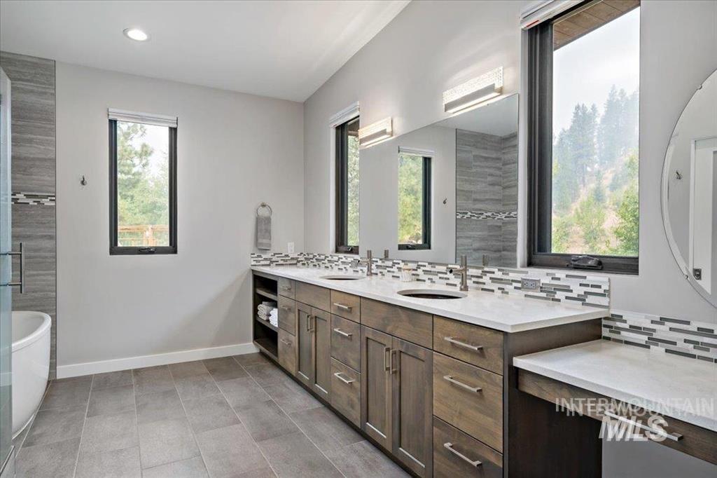 Bathroom featuring tasteful backsplash, a soaking tub, double vanity, and recessed lighting